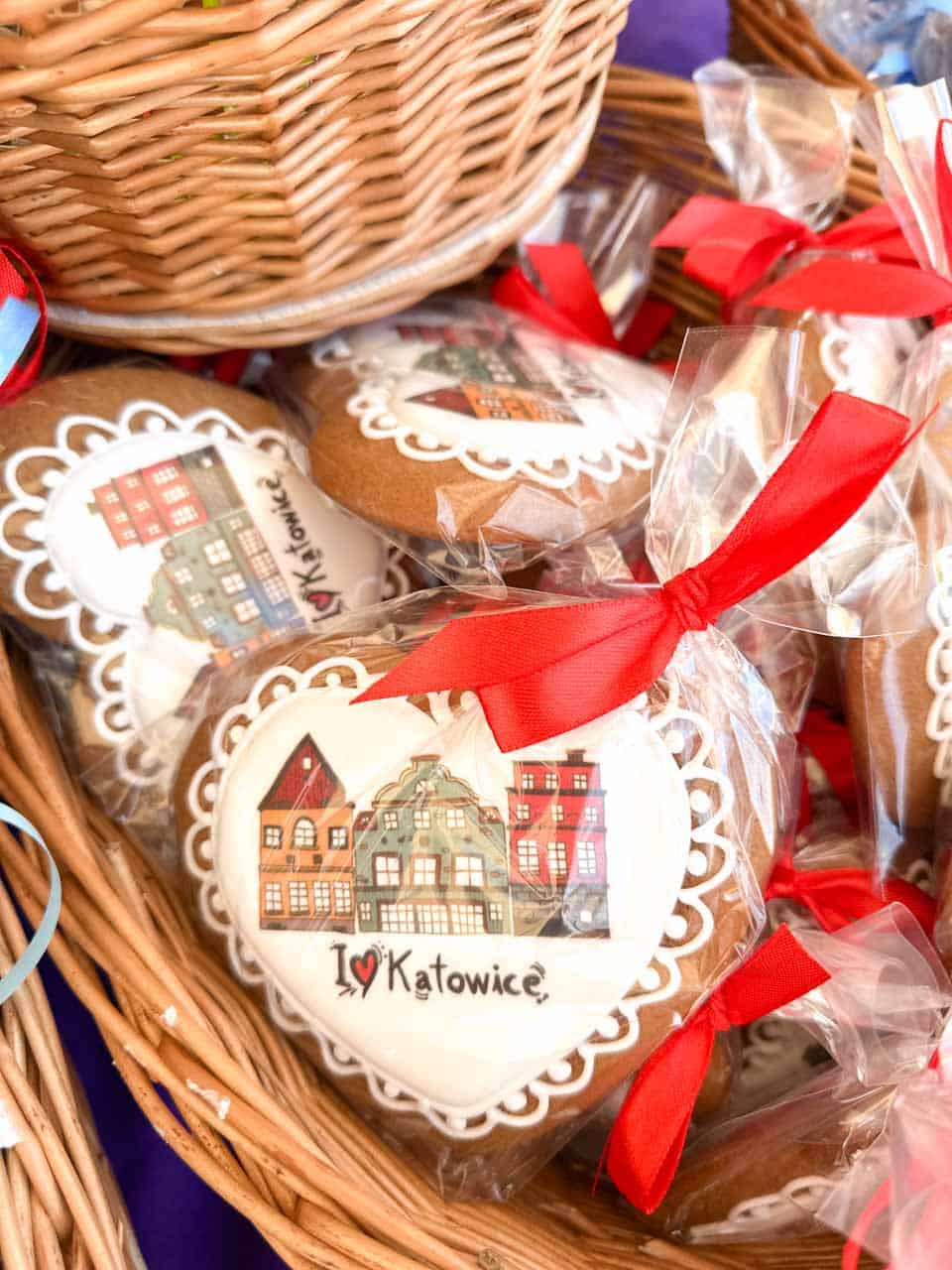 Heart-shaped gingerbread cookies with a Katowice design, wrapped in clear bags with red ribbons