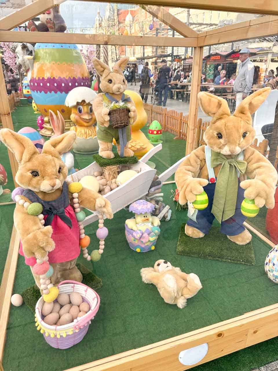 A display of cute Easter bunny figures holding eggs and beads, surrounded by colourful decorations
