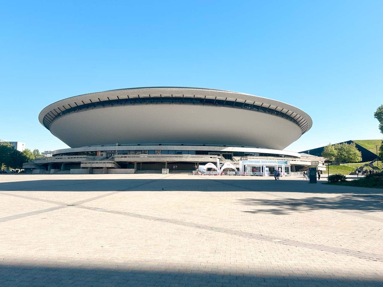The Spodek arena in Katowice, shaped like a flying saucer, seen from a wide open square on a sunny day