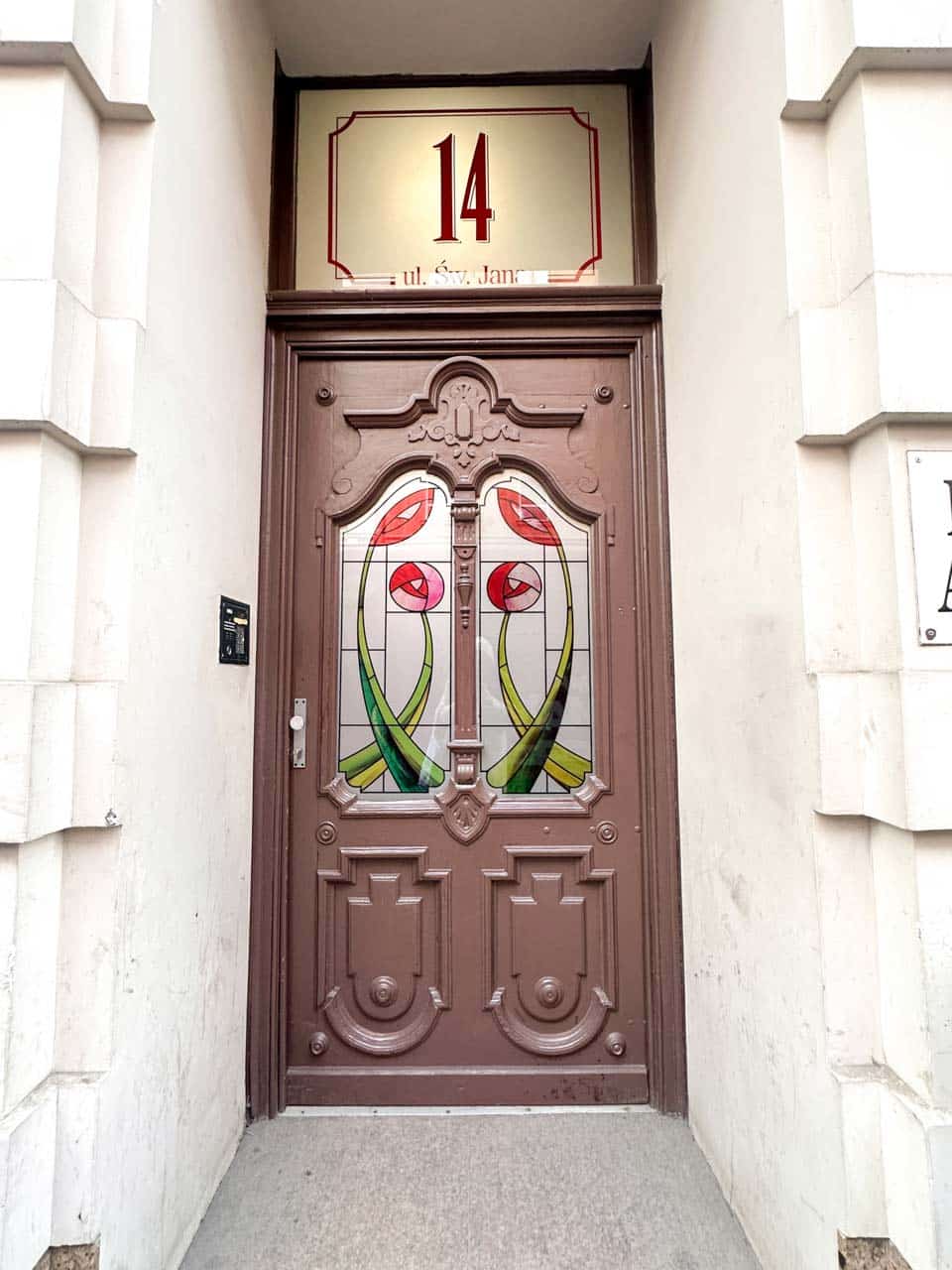 Ornate brown door with stained glass tulips and the number 14 displayed above on Świętego Jana Street in Katowice, Poland