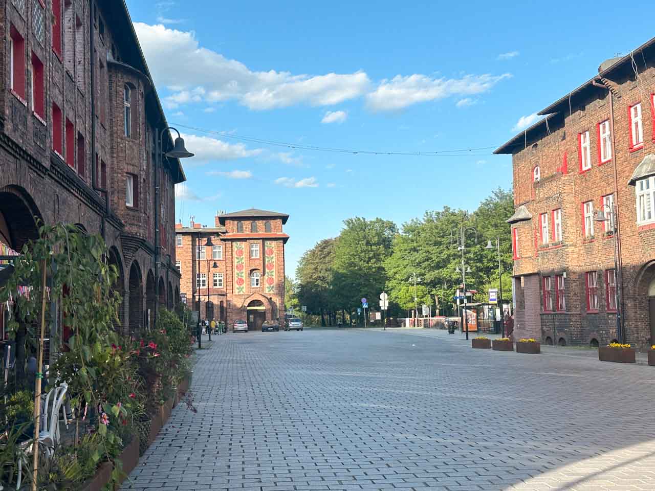 Plac Wyzwolenia (Liberation Square) in Nikiszowiec with red-brick houses, red window frames, and flower planters along the path