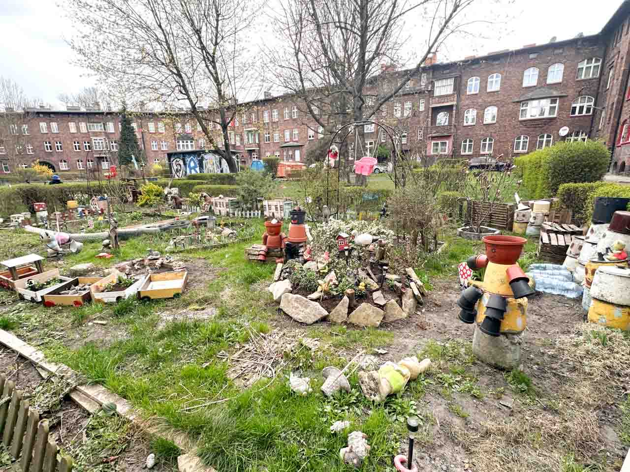A quirky shared garden full of handmade decorations, garden gnomes, planters, and figures made from buckets and pots in the Nikiszowiec district of Katowice