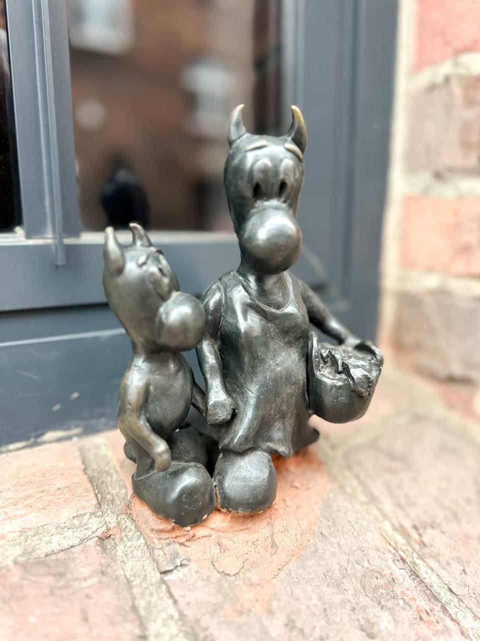 A small bronze statue of two beboks on a windowsill, one carrying a basket