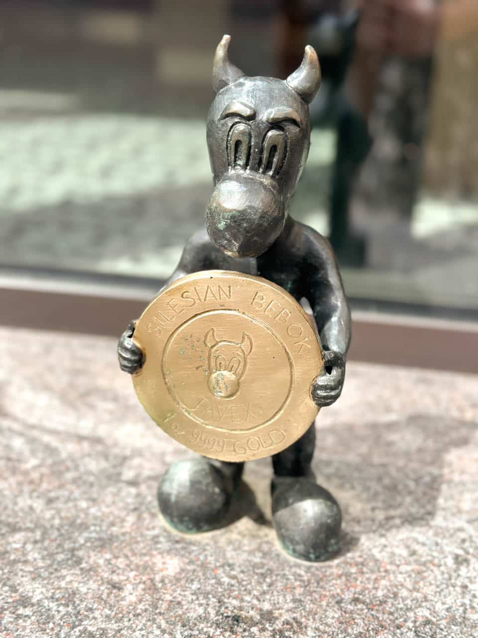 A small bronze statue of a bebok holding a large gold coin that says &ldquo;Silesian Bebok&rdquo;
