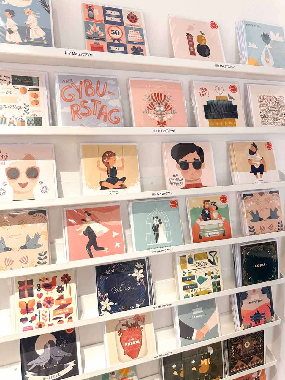 A wall of colourful illustrated greeting cards in Polish, arranged in rows by theme