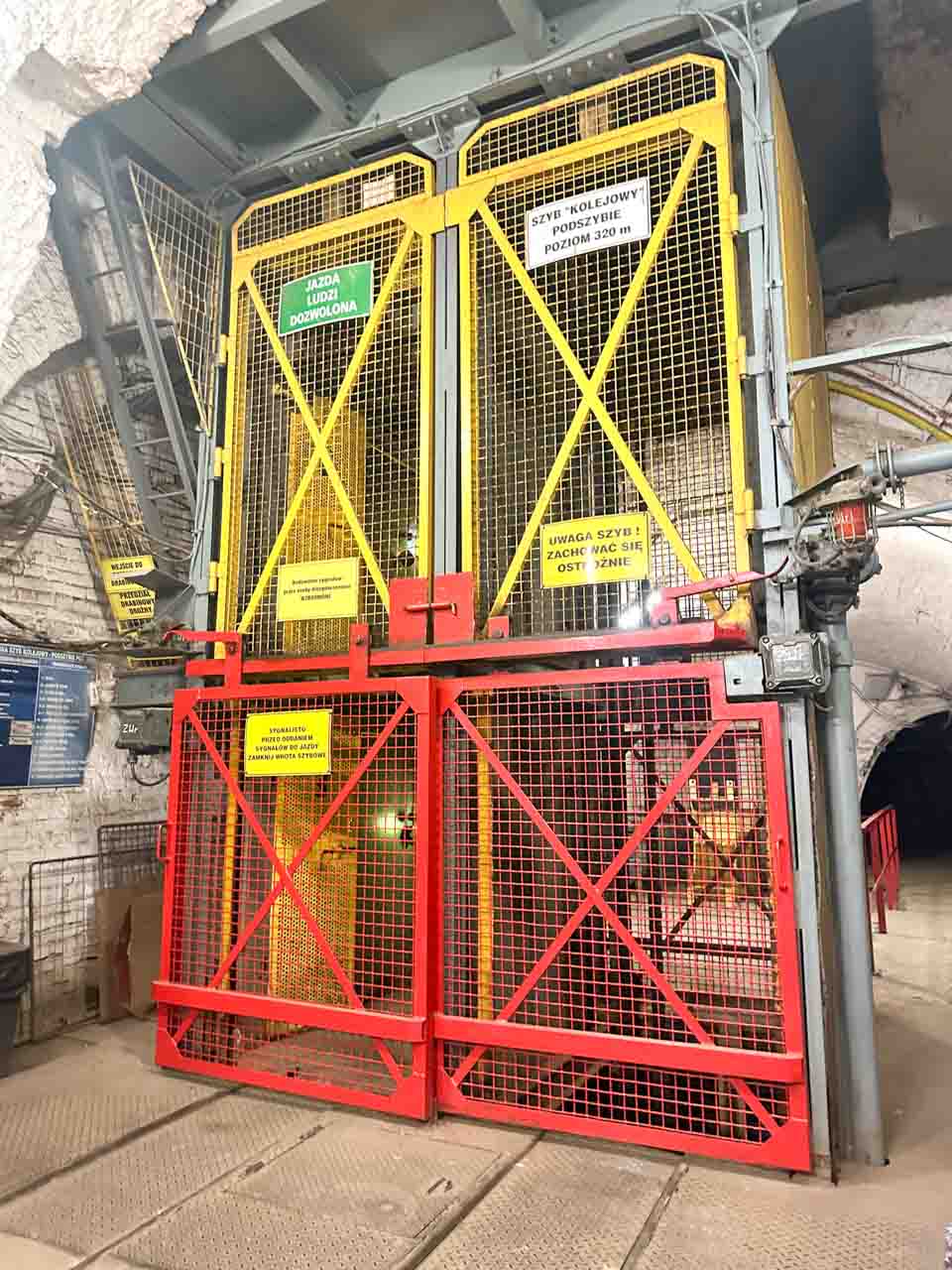 A mining lift cage with red and yellow safety gates inside the Guido Coal Mine in Zabrze, Poland