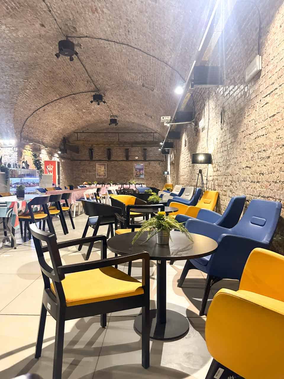 An underground bar at the Guido Mine in Zabrze, with yellow and blue chairs and round tables with potted plants