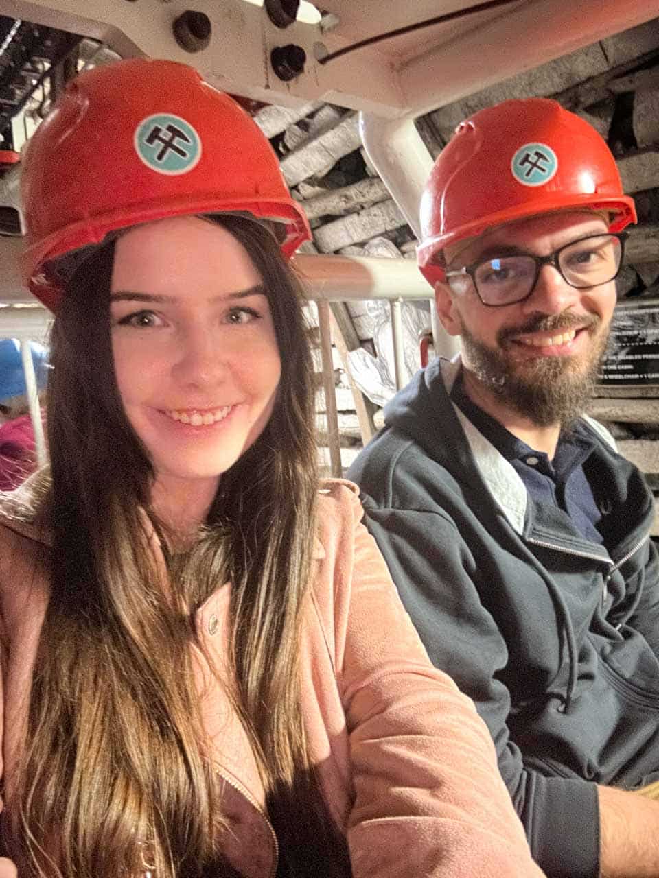 A smiling couple wearing orange mining helmets on a tour inside the Guido Coal Mine in Zabrze, Poland