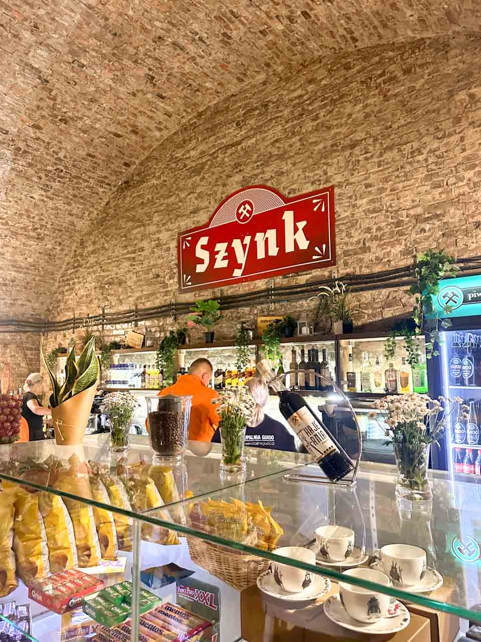 A cosy bar called Szynk inside a brick-vaulted room at the Guido Coal Mine in Zabrze, with snacks, drinks, and shelves of bottles