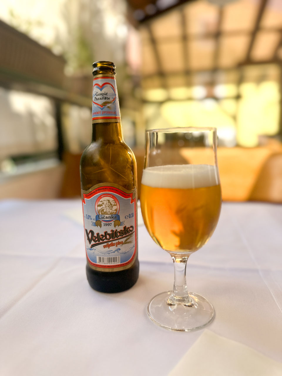 A glass of golden beer and a bottle of Velebitsko lager on a white tablecloth at Konoba Kod Joze in Split, Croatia