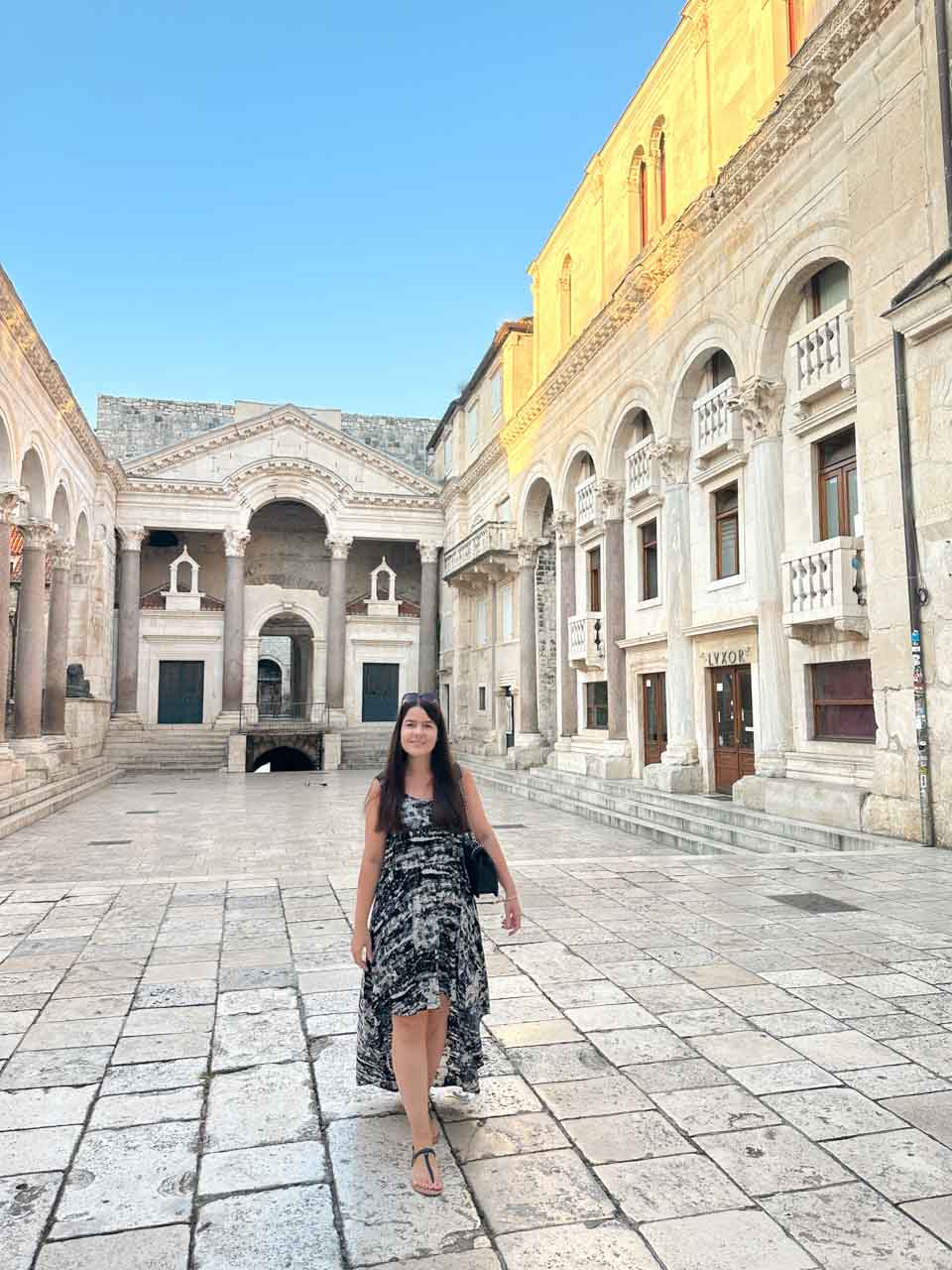 A woman in a patterned dress walking through Peristyle Square in Split