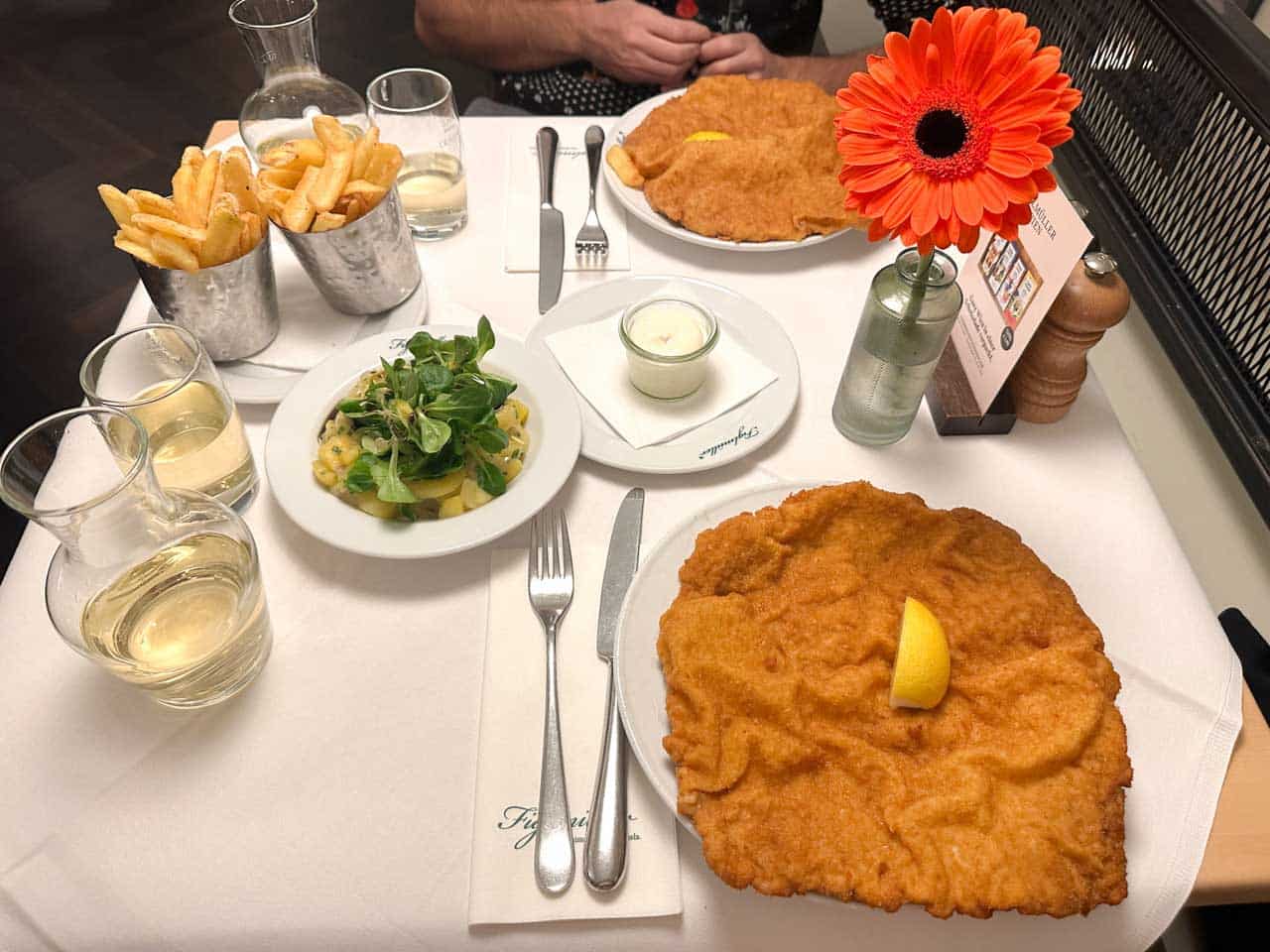 A table at Figlm&uuml;ller with giant schnitzels, chips, potato salad, and glasses of grape juice