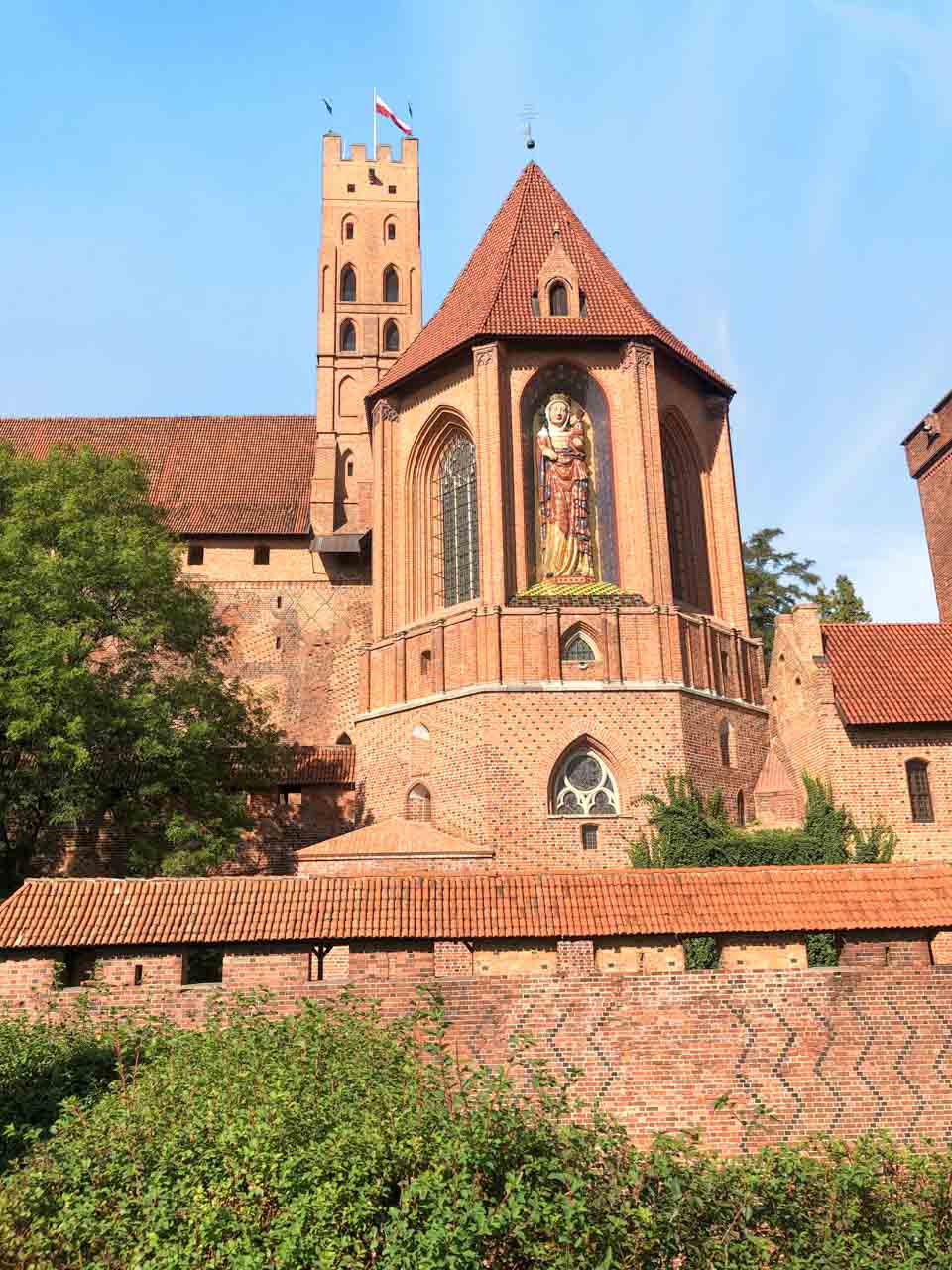 Chapel of St Anne at Malbork Castle with a tall stained glass window and a large mosaic of the Virgin Mary on the outside wall
