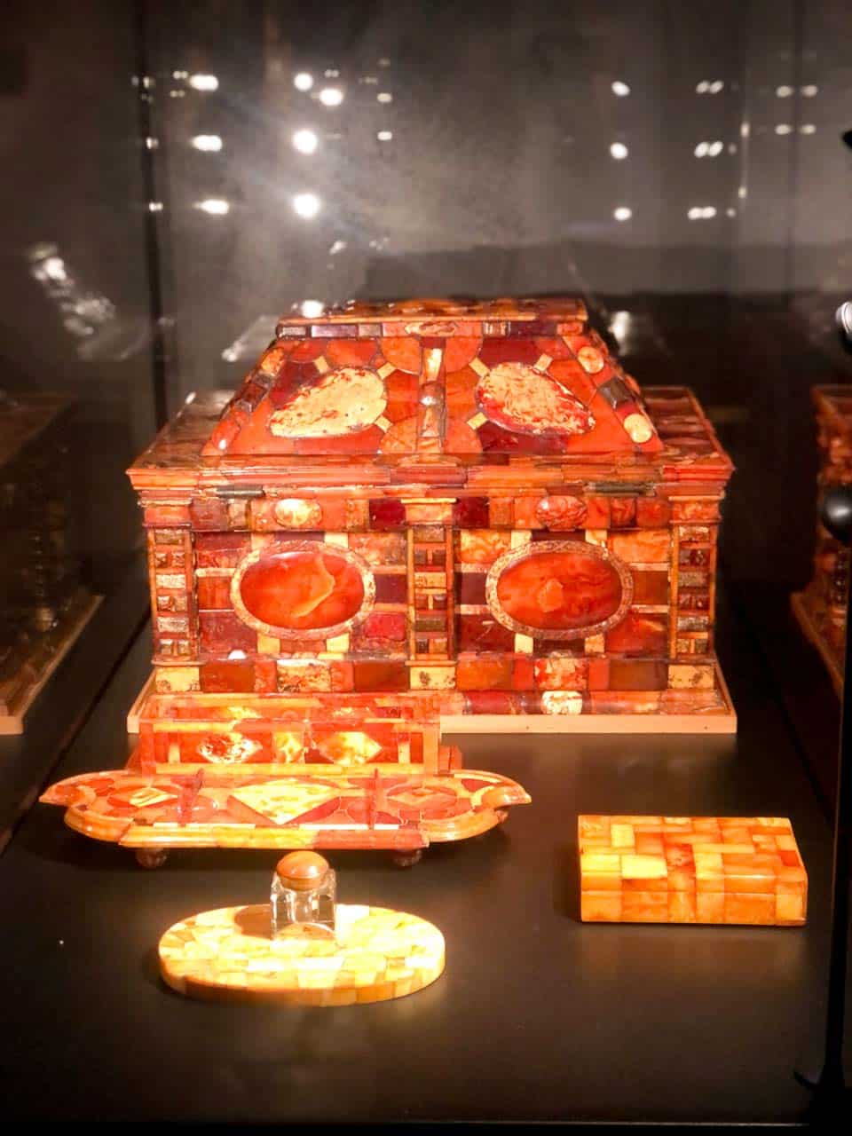 A display of amber objects, including an ornate chest, trays, and a small inkpot, inside Malbork Castle