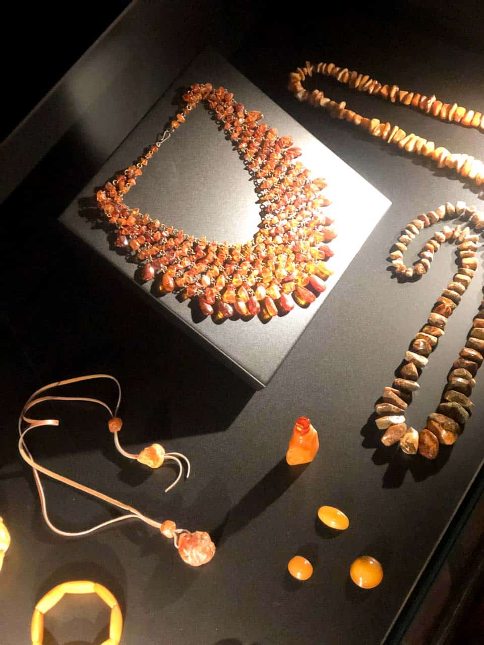 Display of amber jewellery, including chunky necklaces, pendants, bracelets, and small carved pieces