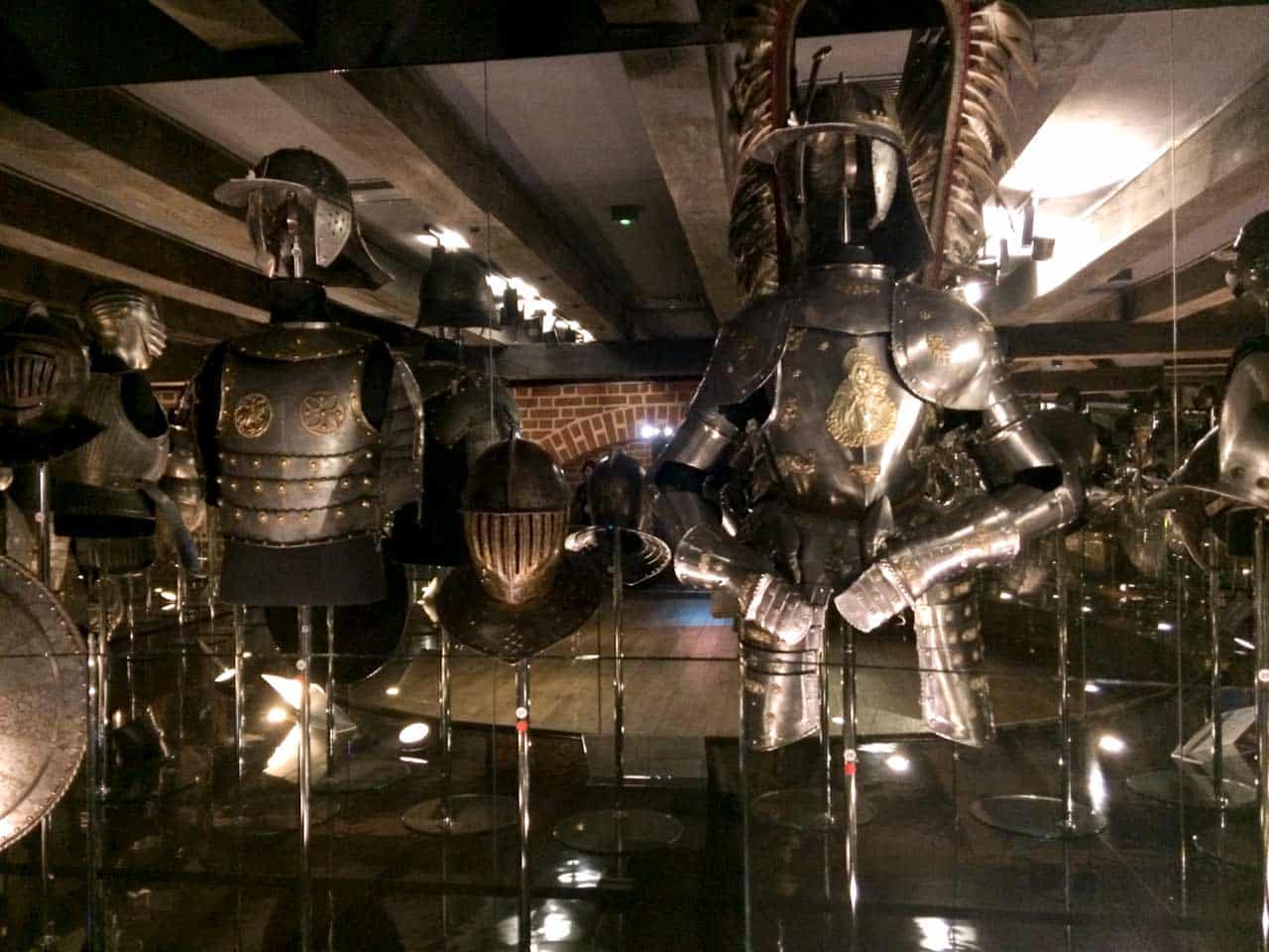 Suits of armour on display in a mirrored room, including a winged hussar set with gold detailing