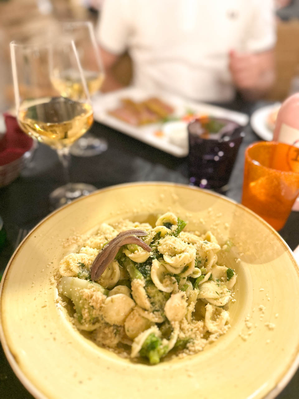 Orecchiette with broccoli, anchovies, and breadcrumbs served on a large yellow plate at La Locanda del Porto in Brindisi, Italy