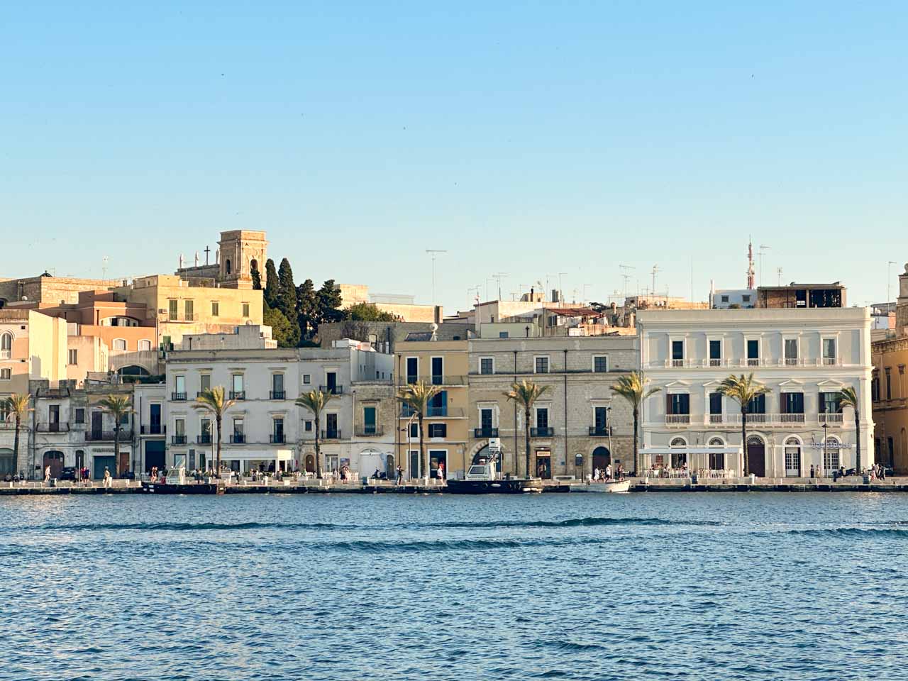 View of Brindisi waterfront with pastel buildings and palm trees lined up along the seafront