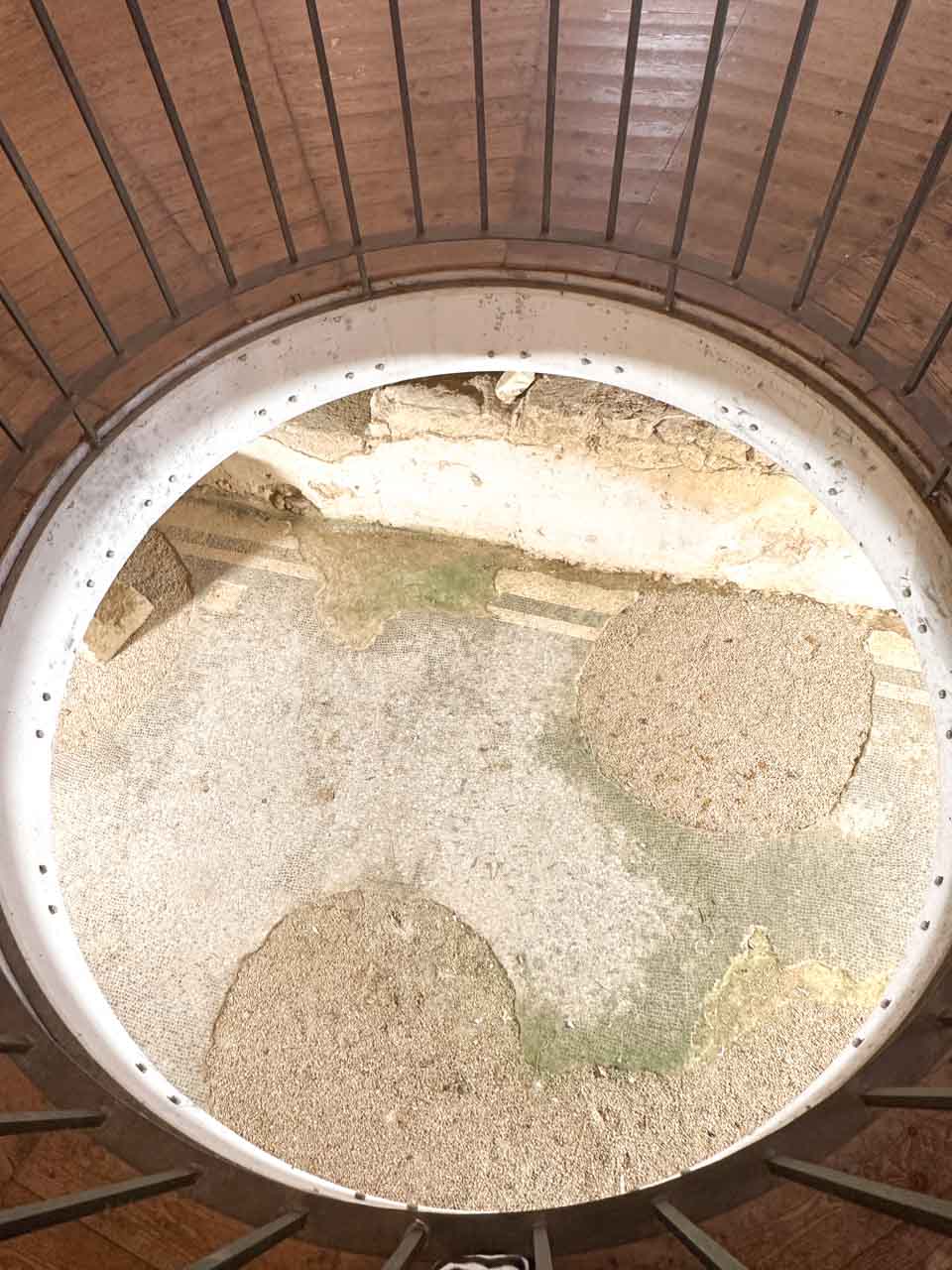 Mosaic floor seen through a circular glass window inside the Church of San Giovanni al Sepolcro in Brindisi, Italy