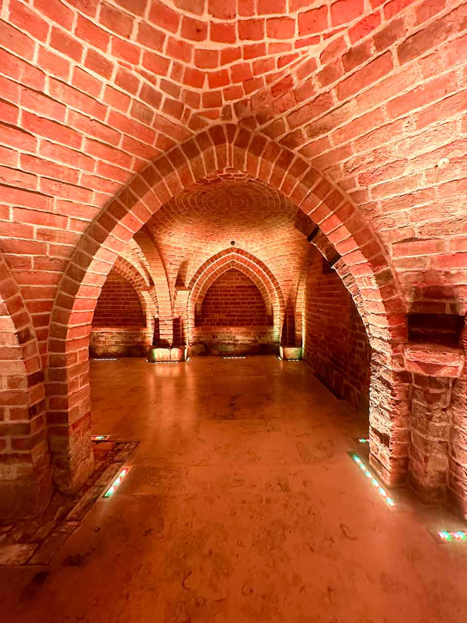 Brick vaulted ceiling with pointed arches and soft lighting inside the Romanesque Cellar in Gdańsk, Poland