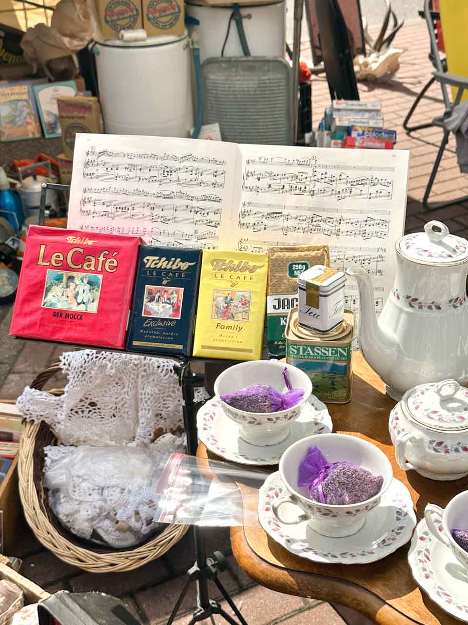 Vintage tea set, coffee tins, and sheet music on display at a flea market stall in Gdańsk