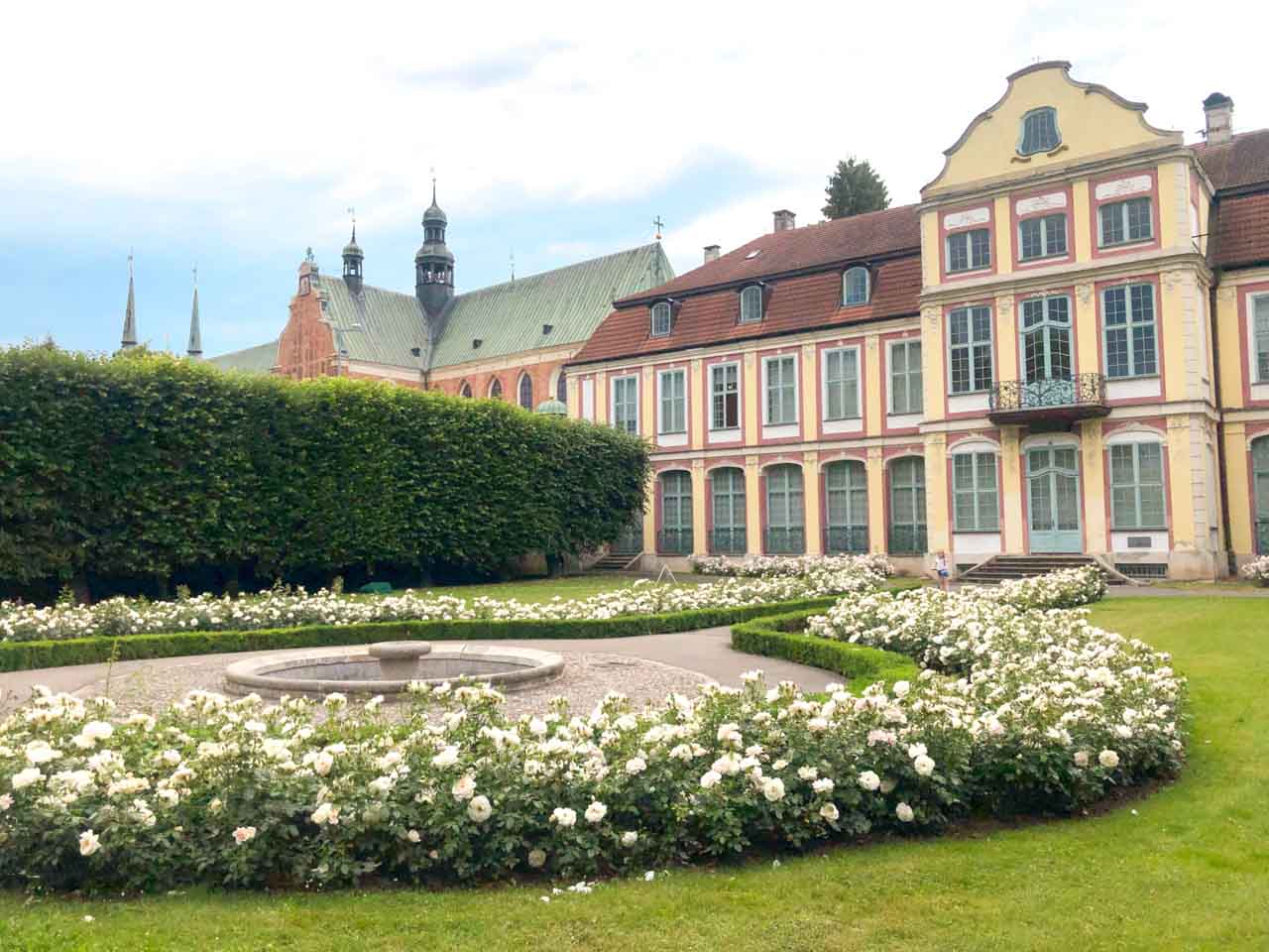 Neatly trimmed rose garden and fountain in front of the Abbots’ Palace and Oliwa Cathedral