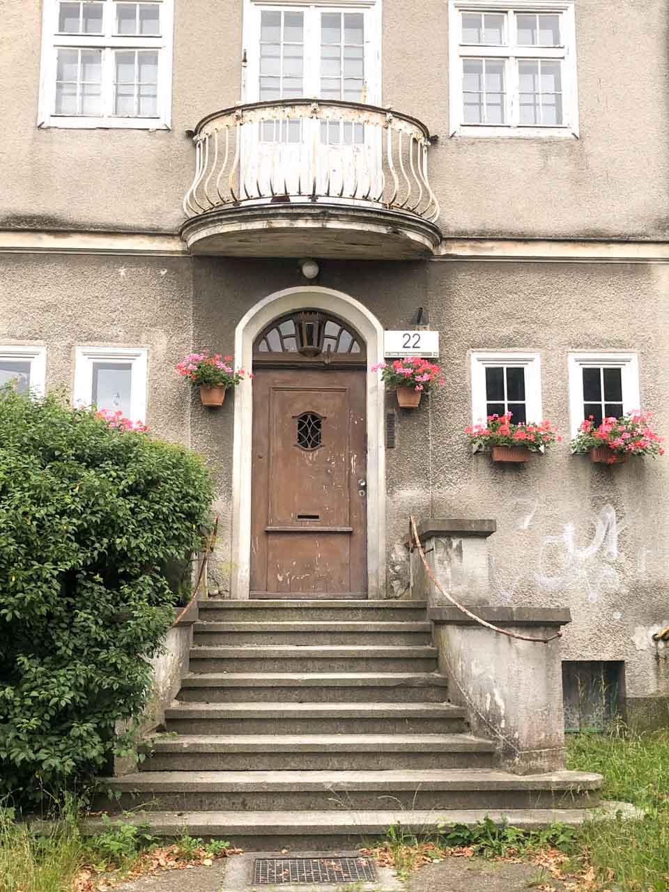 Worn front door with a small balcony and flower boxes on an old building in Gdańsk Oliwa
