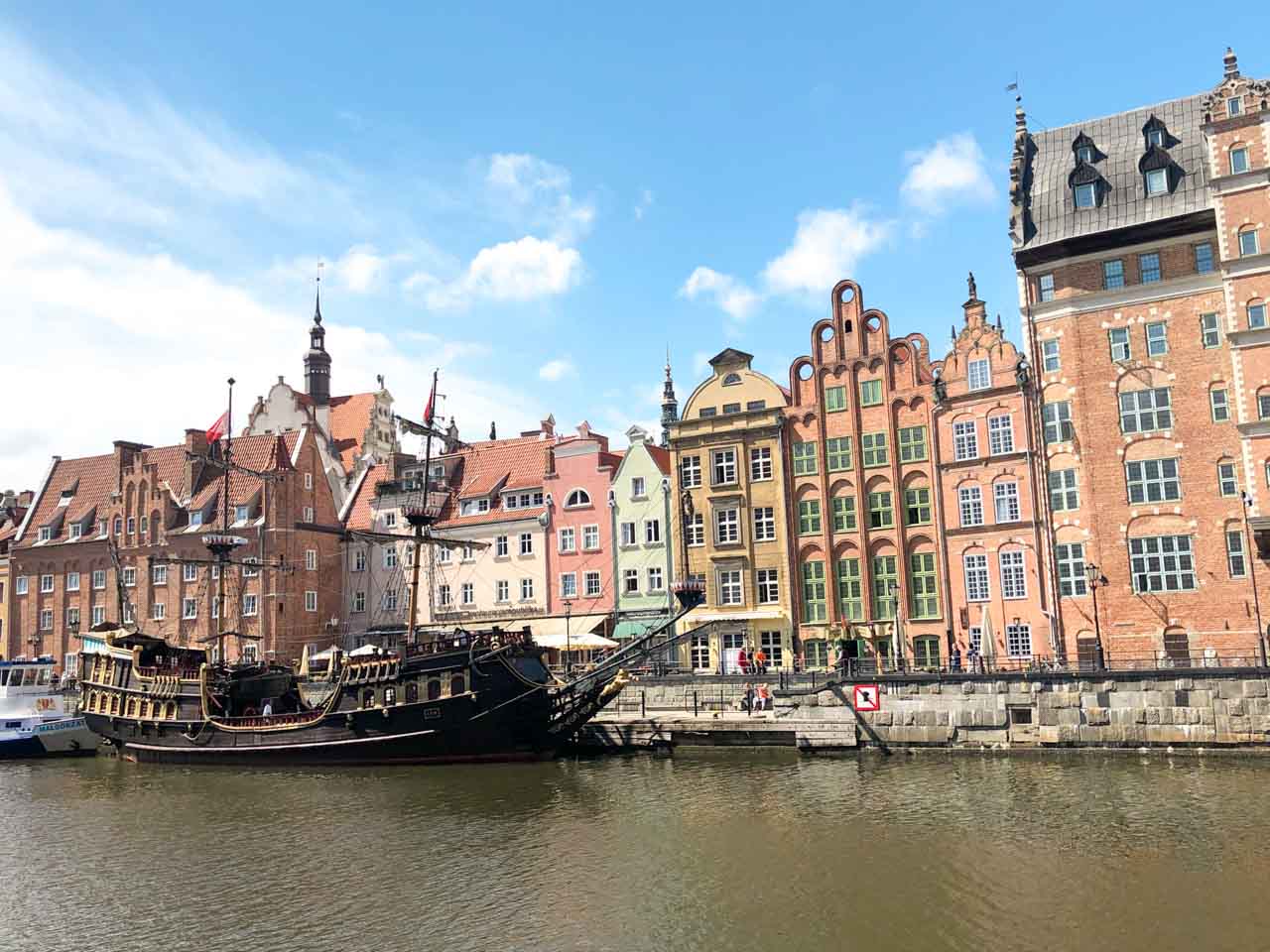 Colourful historic buildings and a replica pirate ship along the Motława River in Gdańsk Main City