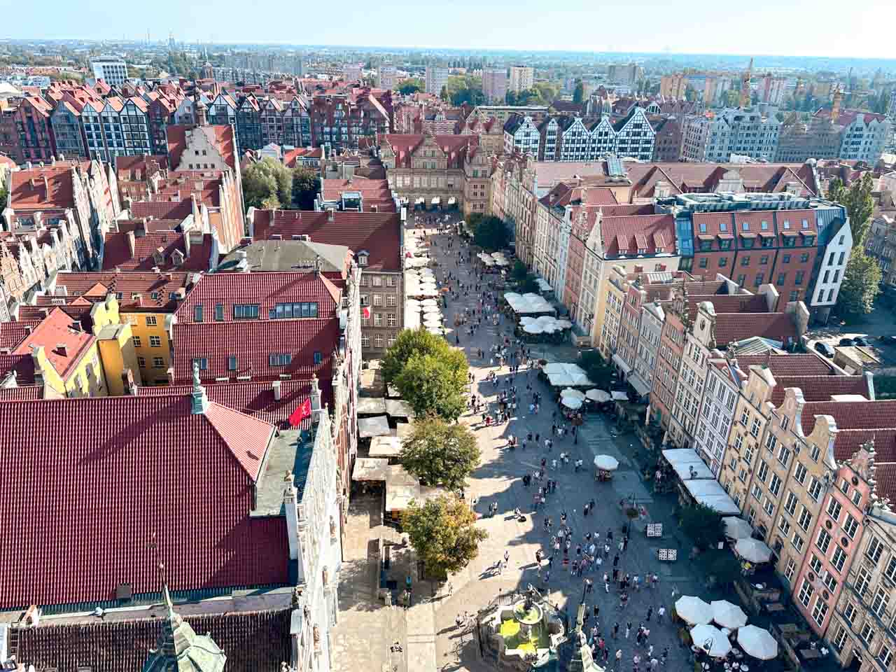 Aerial view of Długi Targ (Long Market) in Gdańsk with umbrellas, people walking, and Neptune's Fountain in the foreground