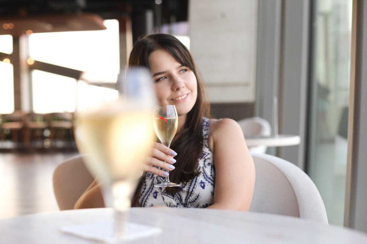 A woman smiling while holding a glass of champagne at Vidokówka inside Olivia Star