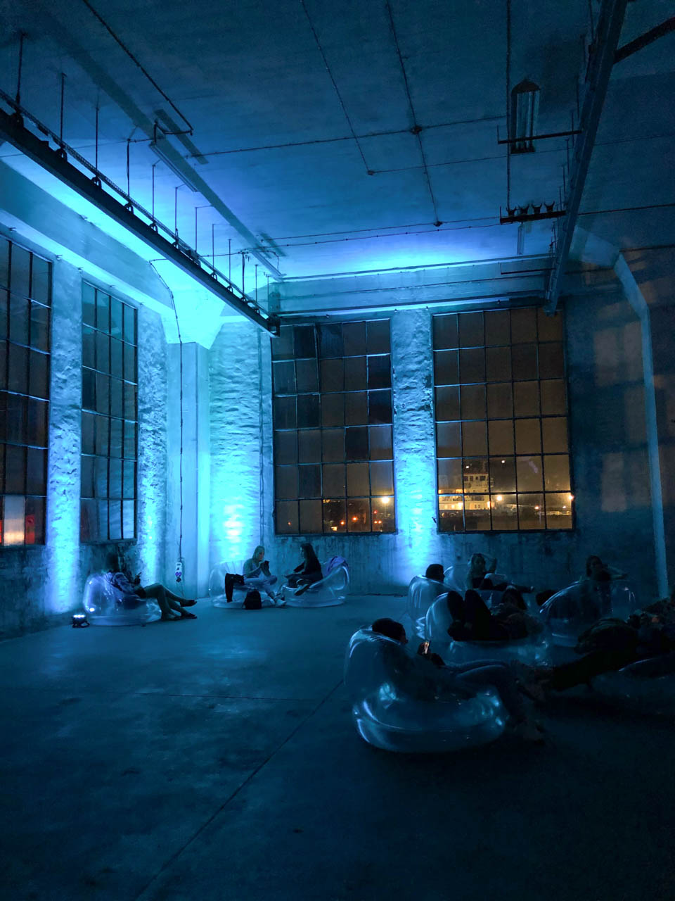 People lounging on inflatable chairs in Plenum, a blue-lit industrial hall on Elektryków Street in Gdańsk