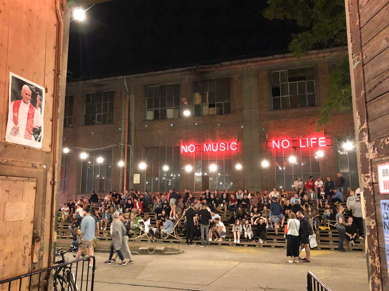 Crowds gathered outside an industrial building on Elektryków Street in Gdańsk, with a glowing ‘No Music No Life’ sign