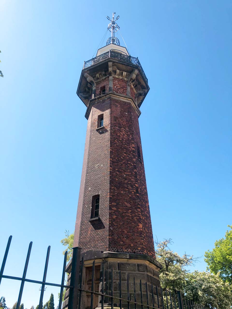 Brick water tower in Gdańsk's Nowy Port district, viewed from below against a bright blue sky