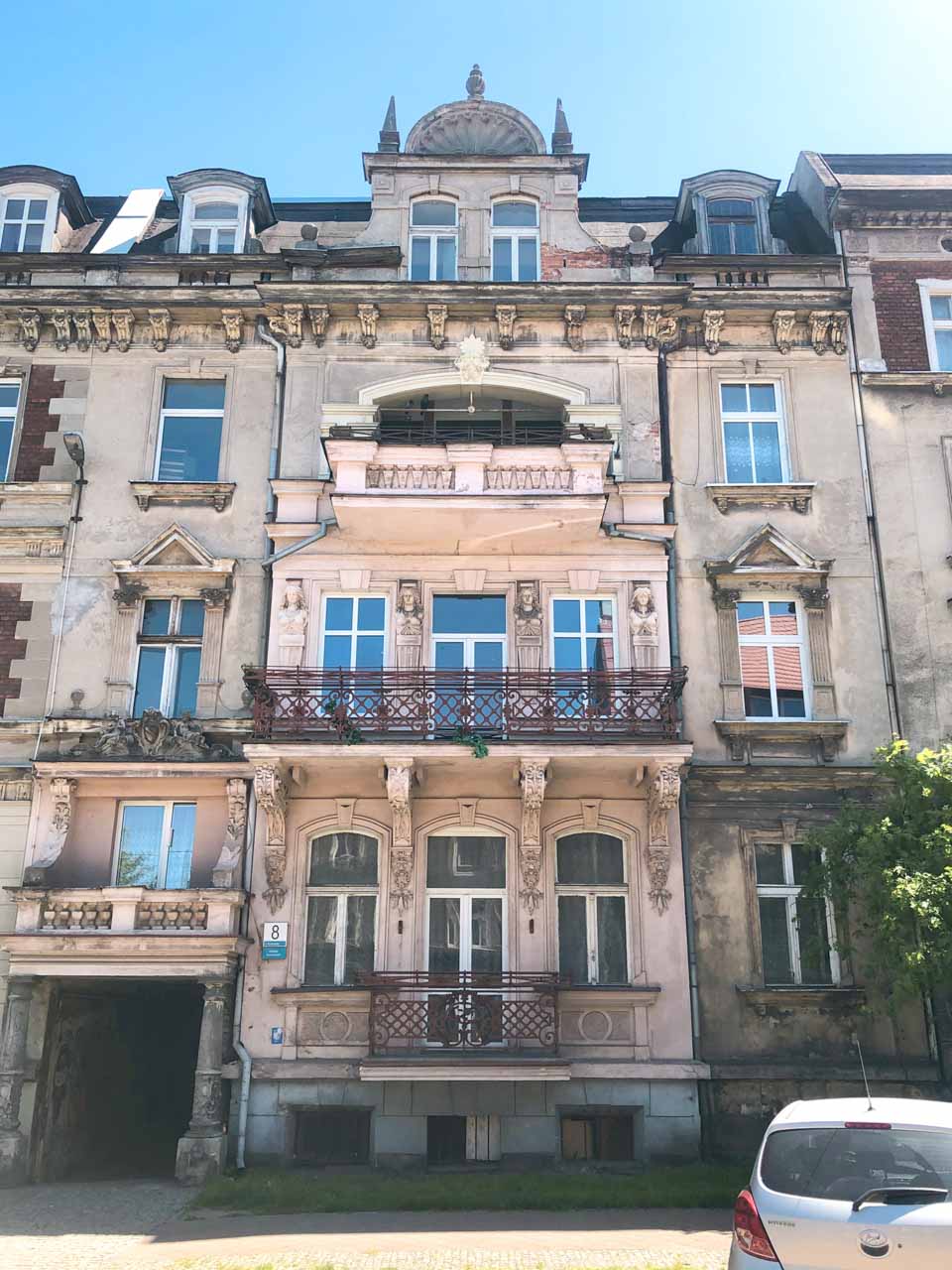 Close-up of a faded but elegant tenement house in Gdańsk Nowy Port, with a pink central balcony