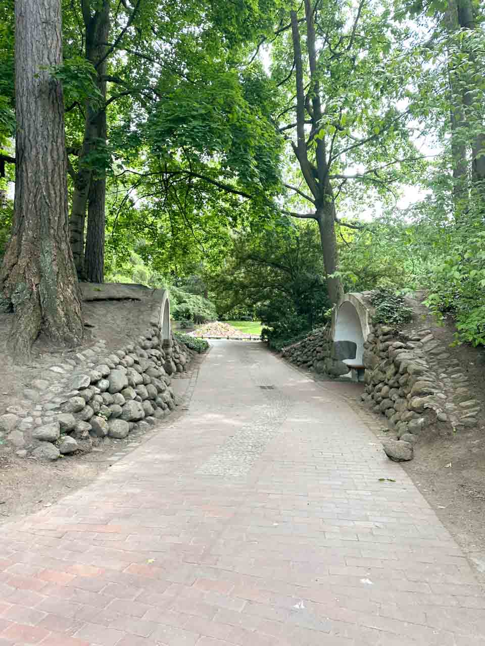 Shaded path with stone caves called the Whispering Caves on both sides in Gdańsk's Oliwa Park