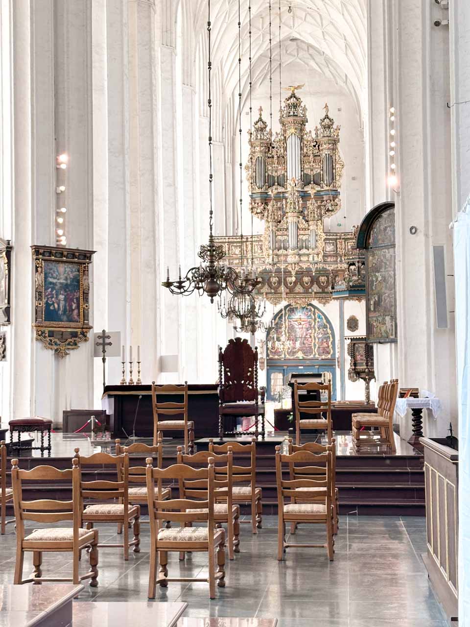 Ornate pipe organ and chandeliers inside St. Mary’s Church, seen from behind a row of wooden chairs