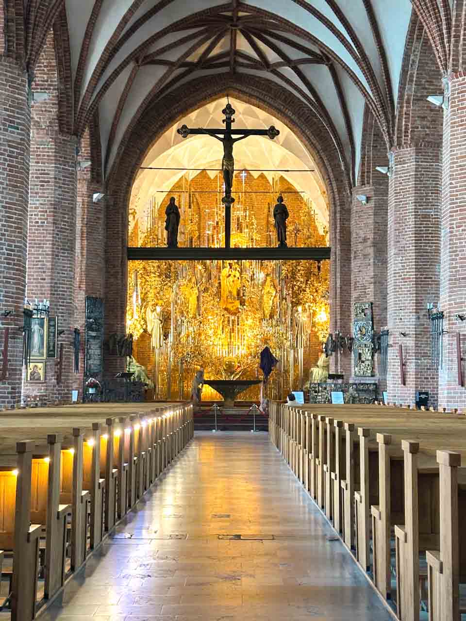 View of the golden Amber Altar at St. Bridget’s Church, seen from between the wooden pews