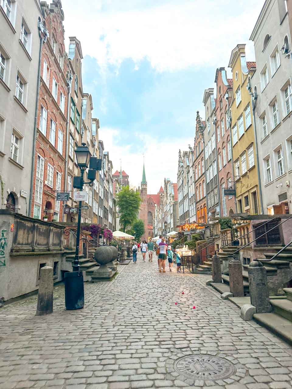 People strolling down Mariacka Street, surrounded by colourful historic buildings and amber stalls