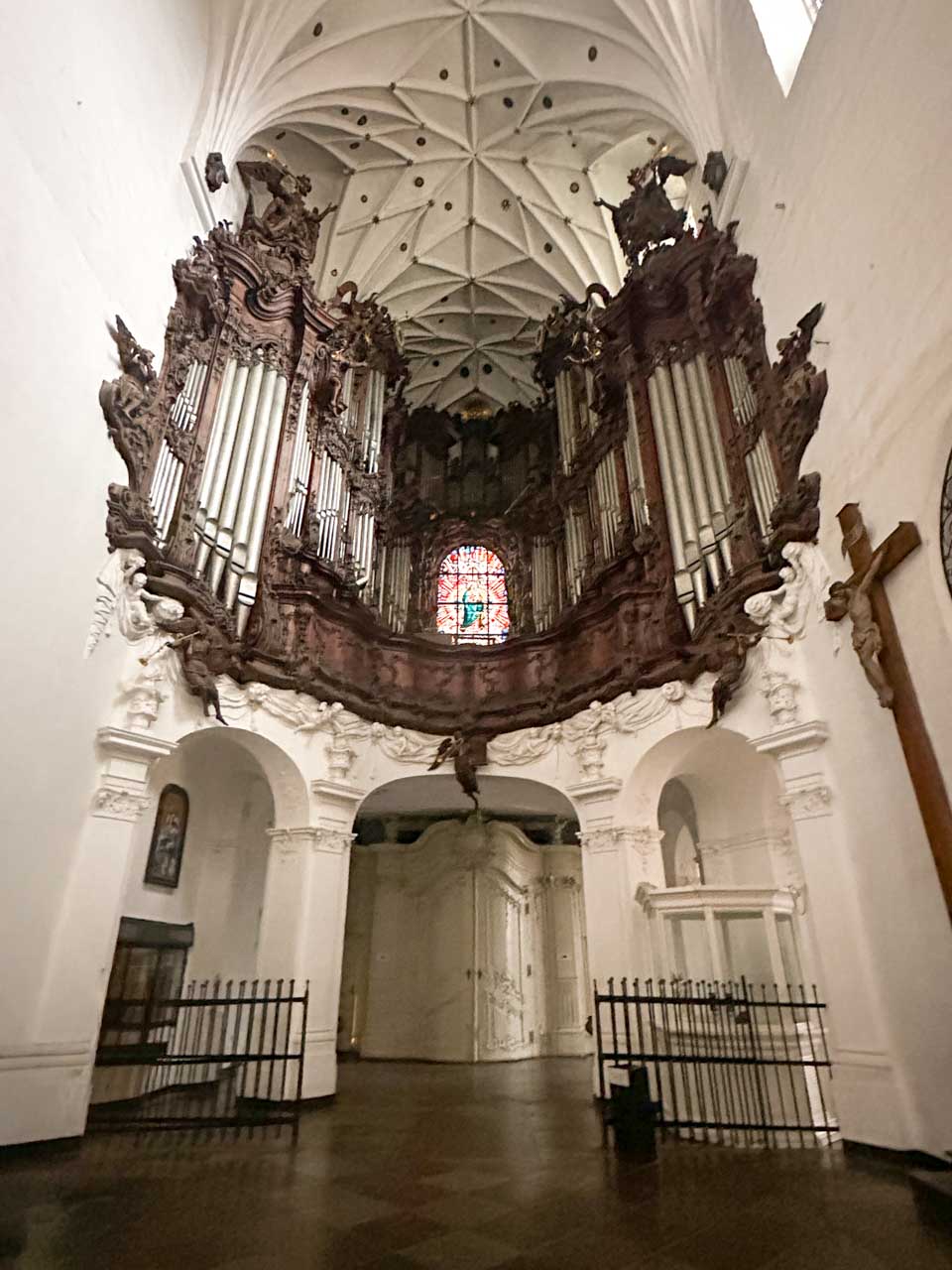 View of the grand pipe organ inside the Oliwa Cathedral in Gdańsk, framed by white walls and arched ceiling