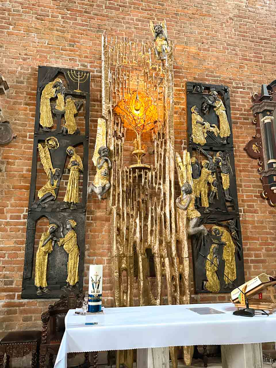 Modern amber tabernacle with religious sculptures on a brick wall inside St. Bridget’s Church in Gdańsk, Poland