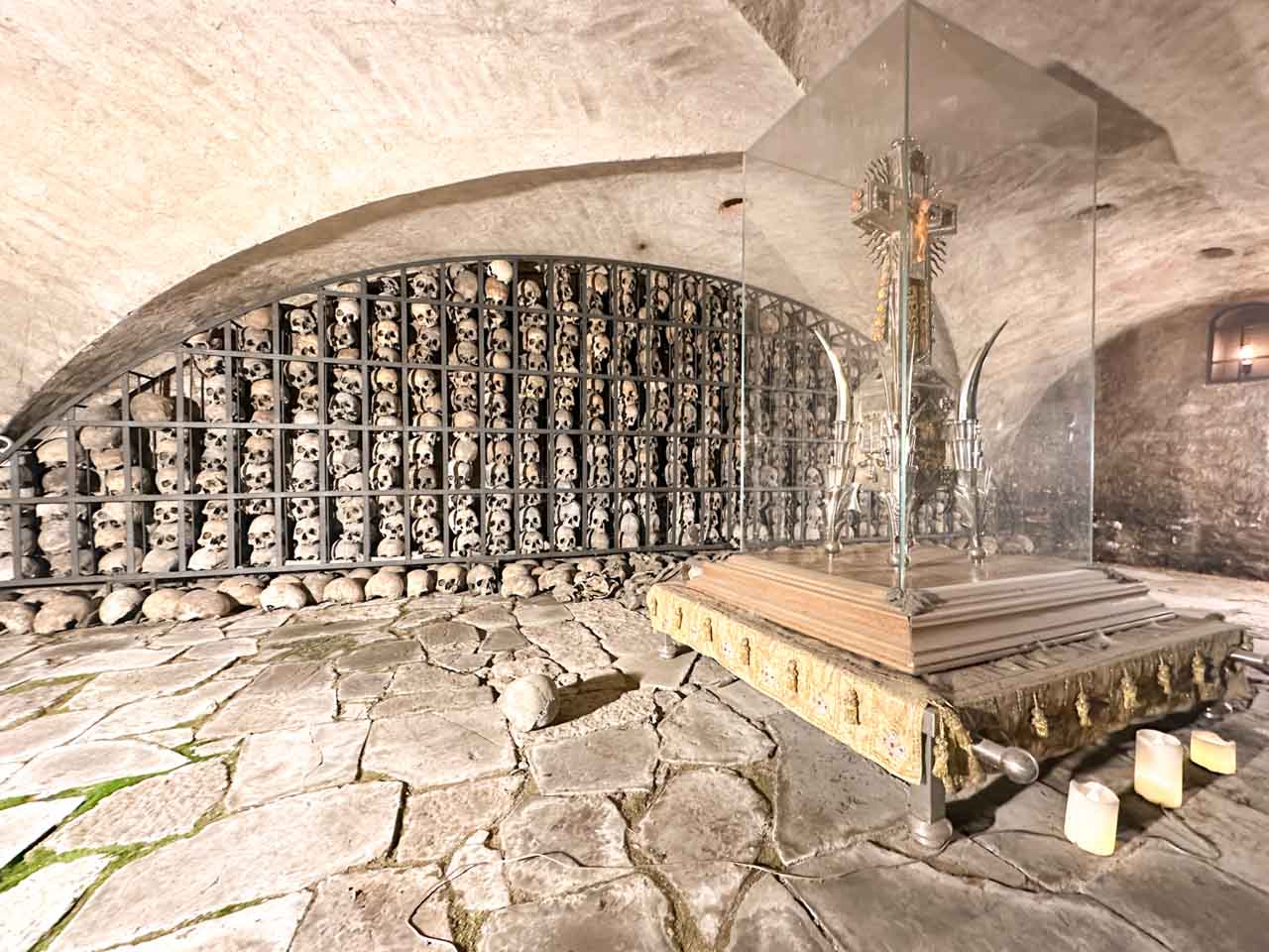 View of the Crypt of Skulls in St. Bridget’s Church, with rows of skulls behind a display case holding a metal reliquary cross