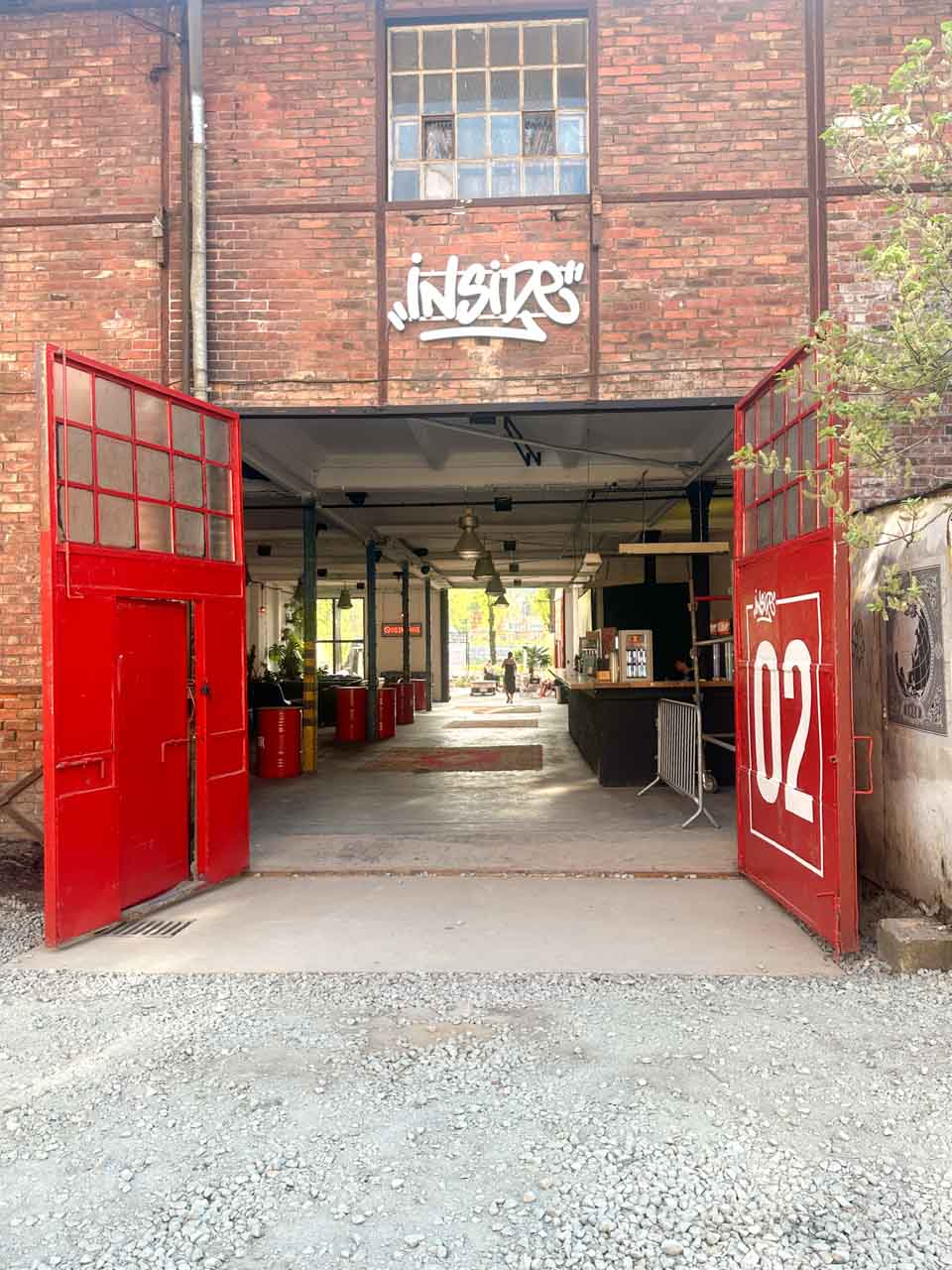 Open red doors leading into an industrial-style space with an ‘Inside’ graffiti above