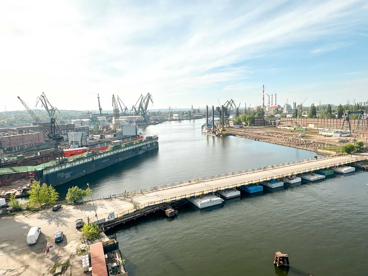 Panoramic view over the Gdańsk shipyard with cranes, factories, and a bridge crossing the water