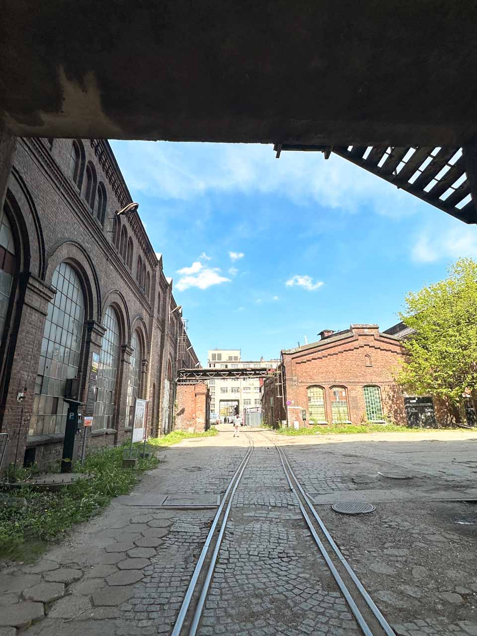Old tram tracks leading through an industrial courtyard surrounded by historic brick buildings in Gdańsk