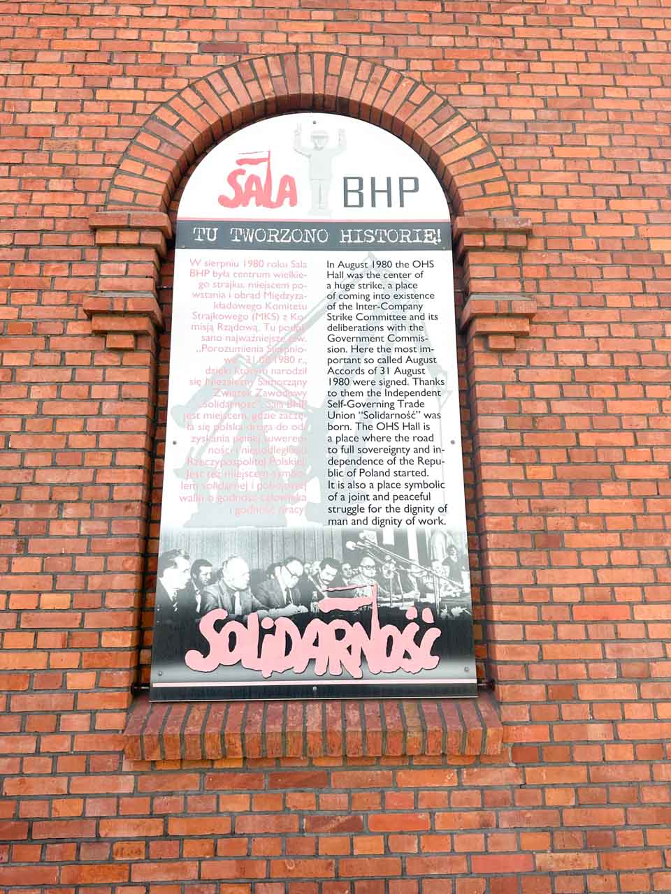 A sign on the brick wall of the OHS Hall, marking the birthplace of the Solidarność movement in 1980