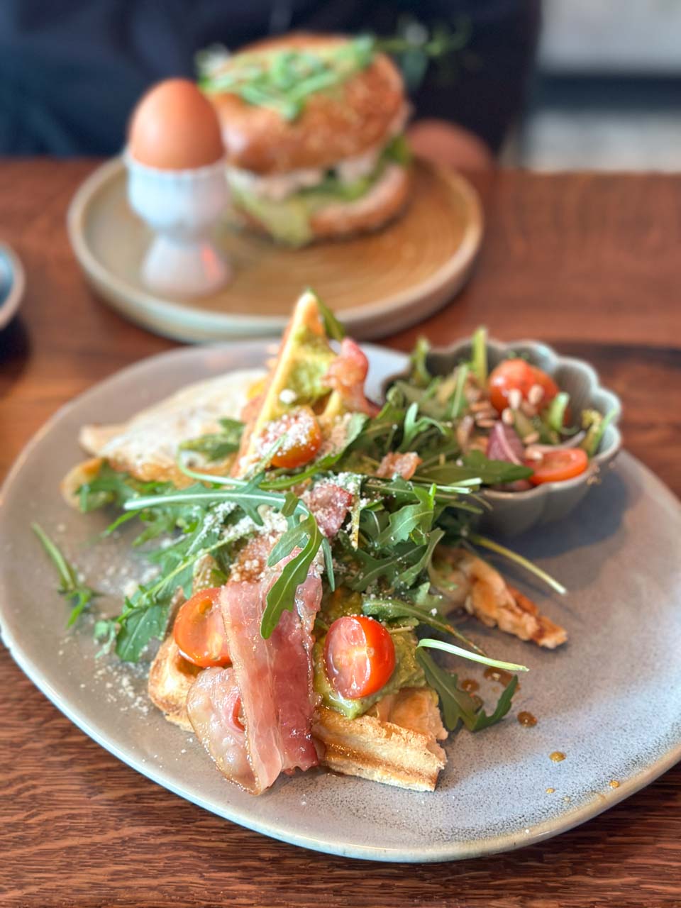 Savoury waffle topped with crispy bacon, cherry tomatoes, rocket, and grated cheese, served with salad at Przystanek Garnizon in Gdańsk