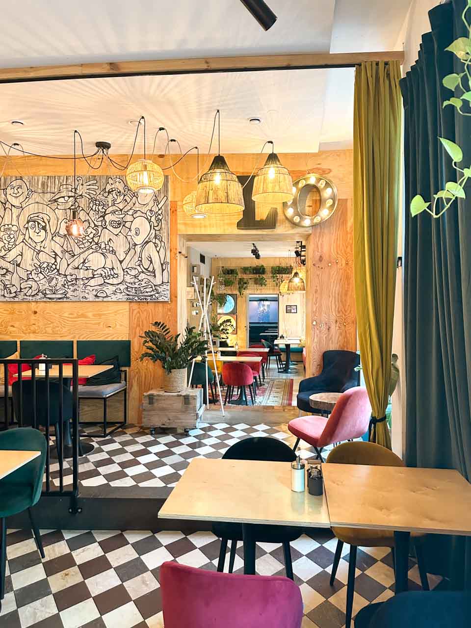 Cosy interior of Pomelo Bistro in Gdańsk with colourful chairs, chequered floor, warm lighting, and playful wall art
