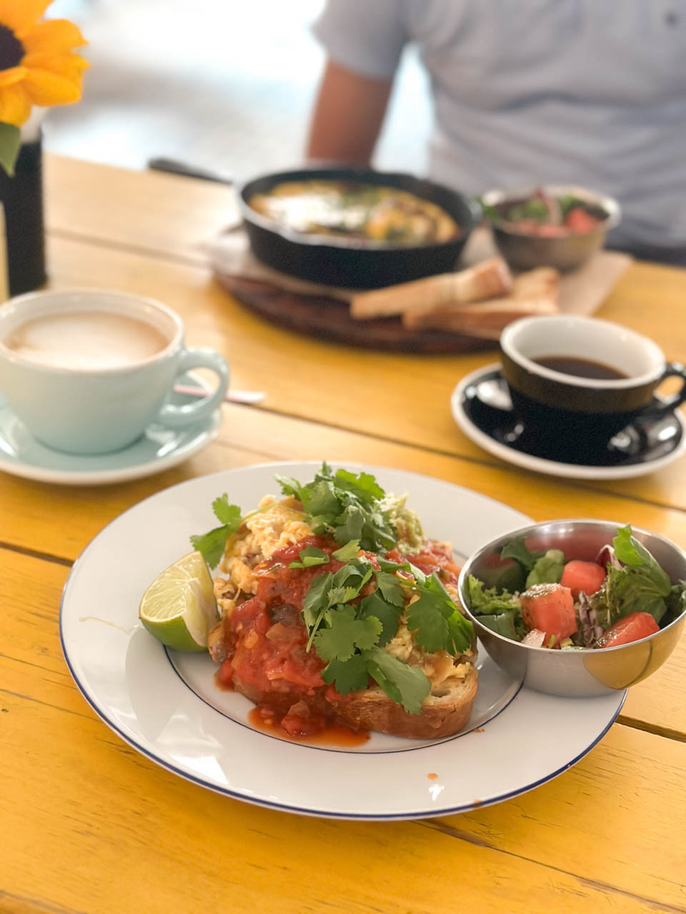 Scrambled eggs on toast with salsa, guacamole, and coriander served with a side salad and coffee at Łąka Bar in Gdańsk