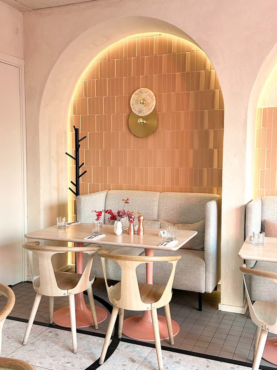 A cosy corner booth at Mimosa in Gdańsk with blush pink tiles and warm arch lighting