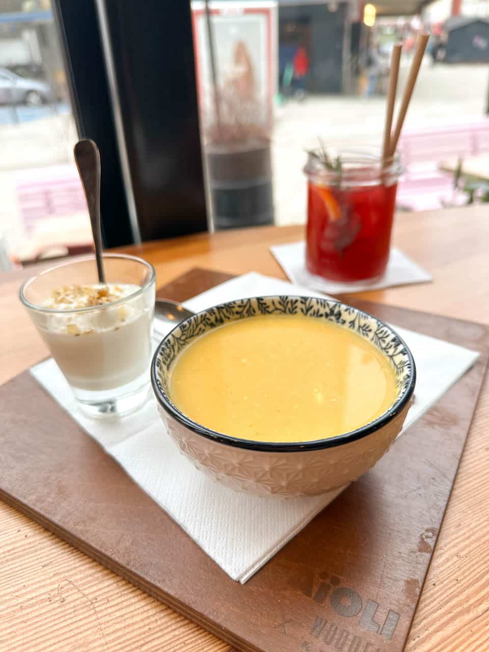 Creamy soup served in a patterned bowl with a small dessert and red lemonade on the side